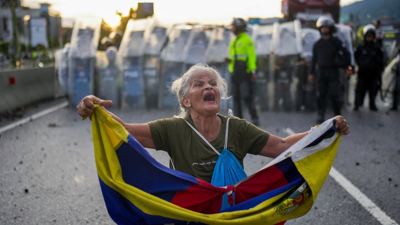 Consuelo Márquez con una bandera de Venezuela al frente de la policía que bloquea las manifestaciones contra los resultados de las elecciones que dieron por ganador a Nicolás Maduro, el día después de las votaciones en Caracas, Venezuela, el lunes 29 de julio de 2024. (AP Foto/Matías Delacroix)
